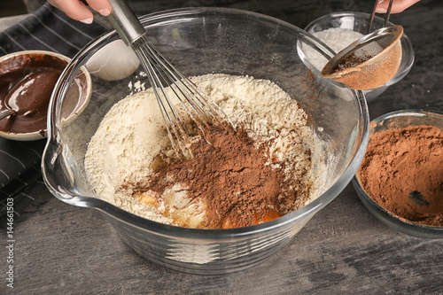 Woman preparing dough for cocoa brownies on table