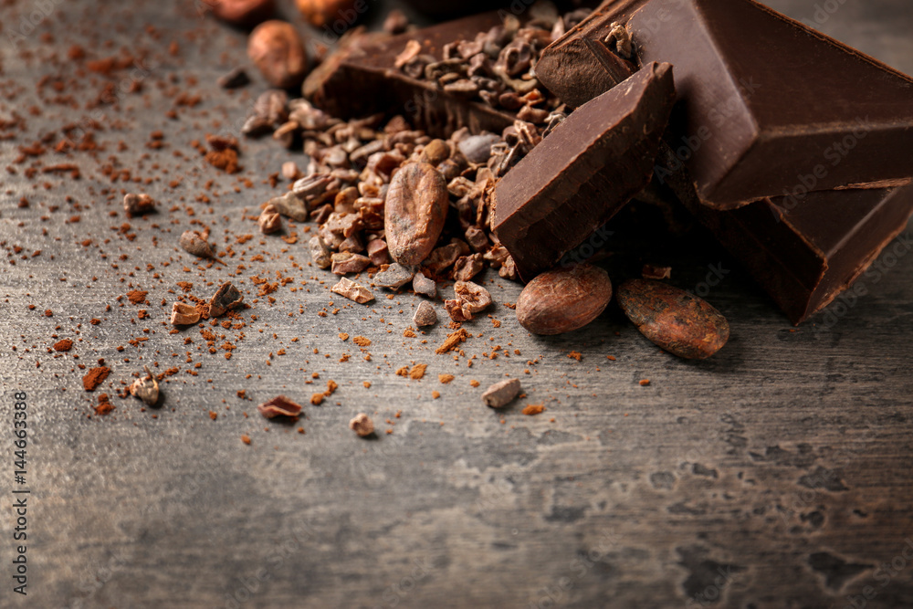 Cocoa beans and pieces of chocolate on table Cocoa beans and pieces of chocolate on table