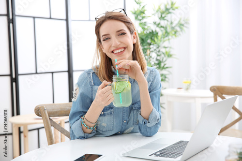 Beautiful young woman with lemonade and laptop in cafe