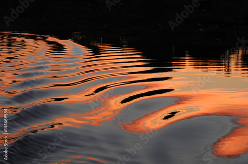 Ripples on the water reflect the sunset on the clouds into the water