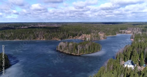 Sahajarvi, Cinema 4k aerial of a island at icy sahajarvi lake, on a sunny spring day, in nuuksio national park, in Espoo, Finland photo