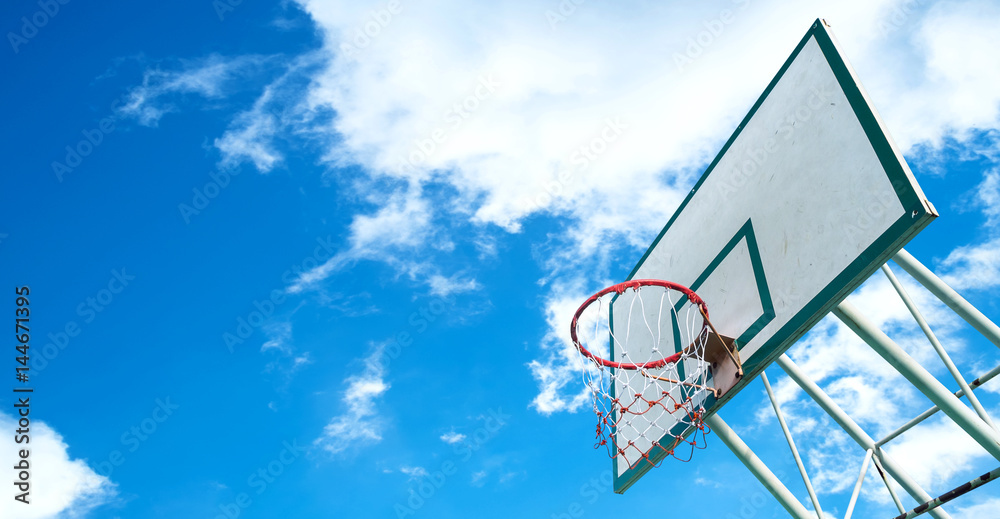 Basketball hoop on a blue sky with clouds.