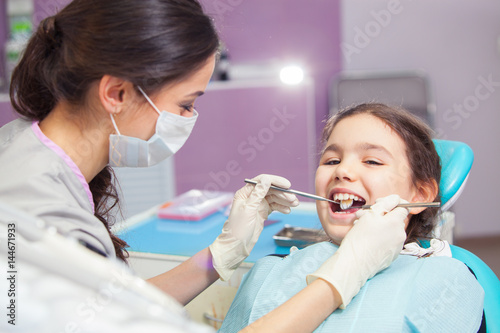 Close-up of pretty little girl opening his mouth wide during treating her teeth by the dentist