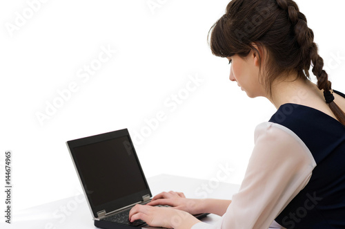 Portrait of young pretty business woman in white and blue suit prints on laptop keyboard sitting at her workplace in office.