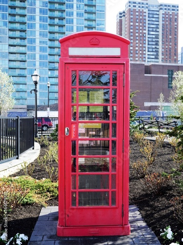 Imitation classic British London red phone booth in a park with modern highrise building in the background photo