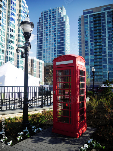 Imitation classic British London red phone booth in a park with modern highrise building in the background photo