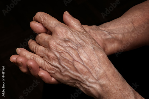 Folded senior woman wrinkled hands close up. Old age, age problems, poverty and loneliness theme