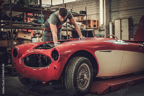 Foto Mechanic working on classic car electrics in restoration workshop