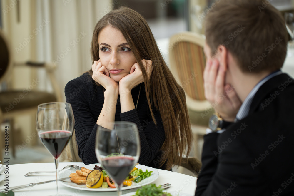 Young woman making an exasperated expression gesture on a bad date at the restaurant Young woman making an exasperated expression gesture on a bad date at the restaurant