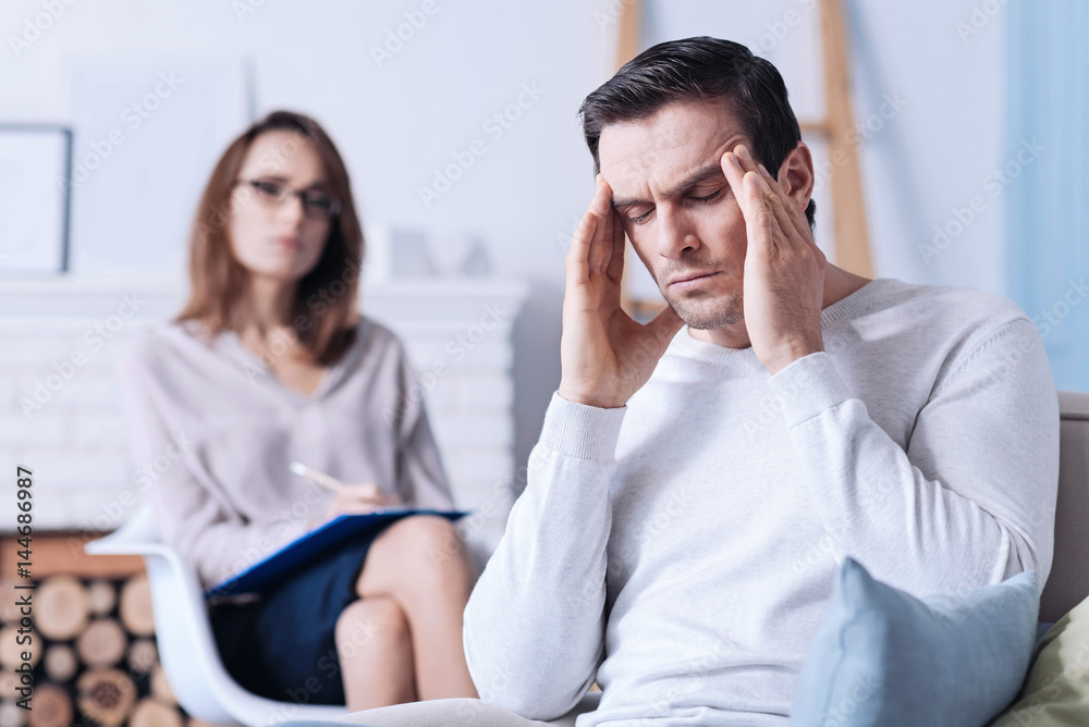 Cheerless unhappy man rubbing his temples Cheerless unhappy man rubbing his temples
