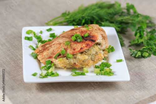 The baked chicken fillet with a stuffing in sauce with seasonings on a gray background
