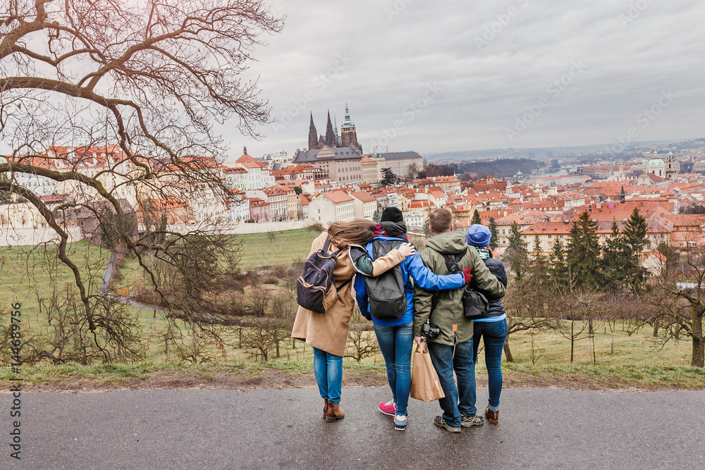 Naklejka premium Back view of group of people hugging in Prague park at spring. Travel with friends concept