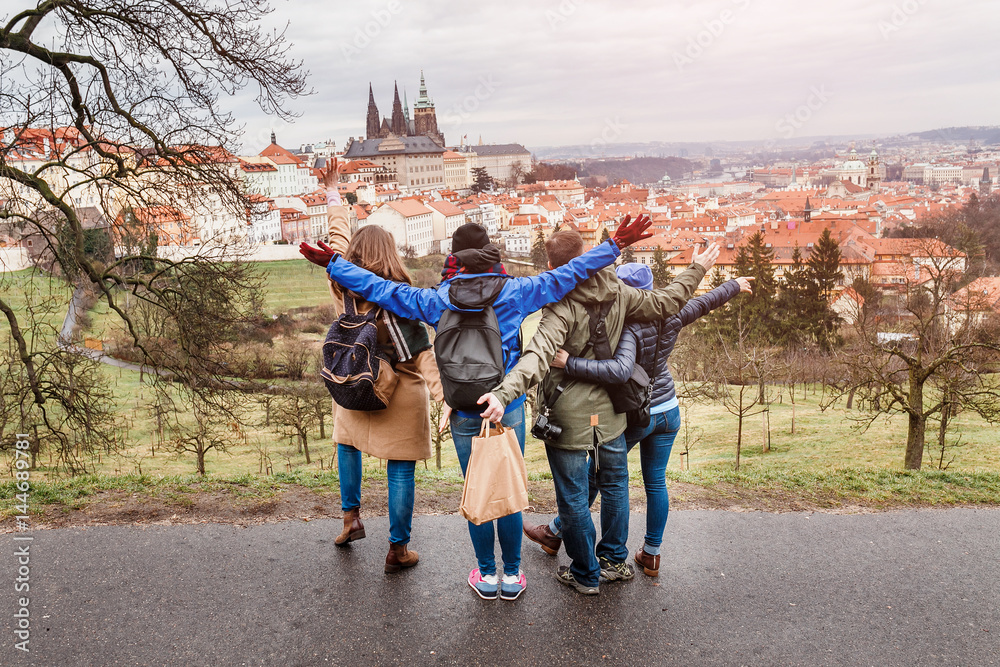 Naklejka premium Widok z tyłu grupy ludzi przytulających się w parku w Pradze na wiosnę. Koncepcja podróży z przyjaciółmi