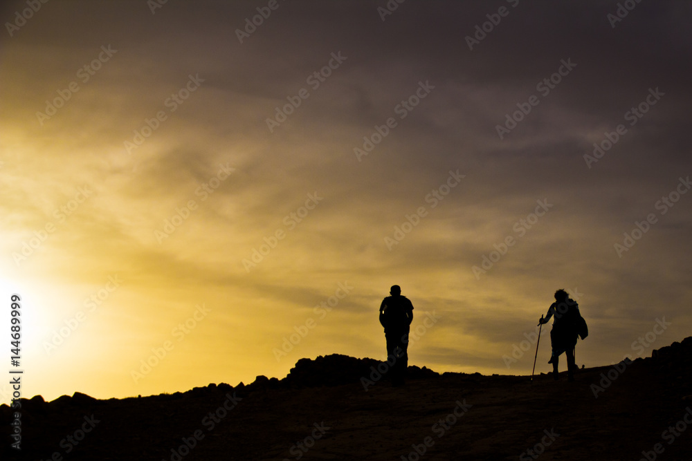 silhouettes on top of mountain in sunset