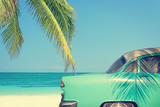 Classic car on a tropical beach with palm tree, vintage process