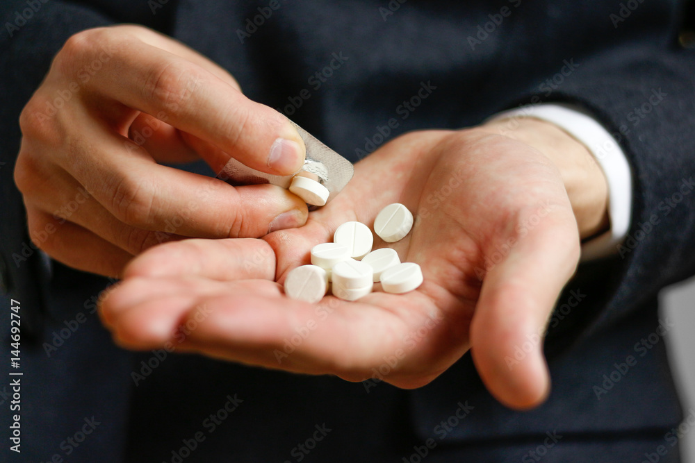 Close up of man's hand taking out pills from blister pack Close up of man's hand taking out pills from blister pack