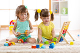 Children playing together with building blocks. Educational toys for preschool and kindergarten kids. Little girls build toys at home or daycare.
