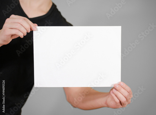 Man in black t shirt holding blank white A4 paper. Leaflet presentation. Pamphlet hold hands. Man show clear offset paper. Sheet template.