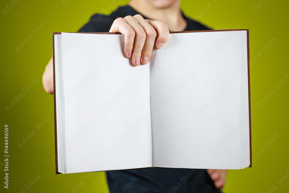 Closeup of guy in black t-shirt holding blank open white book on isolated background. Education concept. Mock up Closeup of guy in black t-shirt holding blank open white book on isolated background. Education concept. Mock up