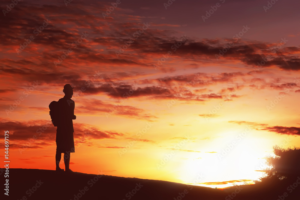Silhouette hiker man with backpack standing enjoying sunset