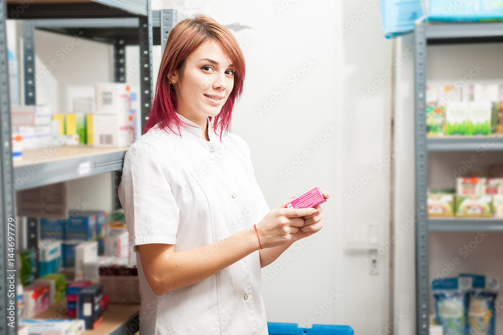 Pharmacist woman in the storage facility next to the shelfs. Healthcare business