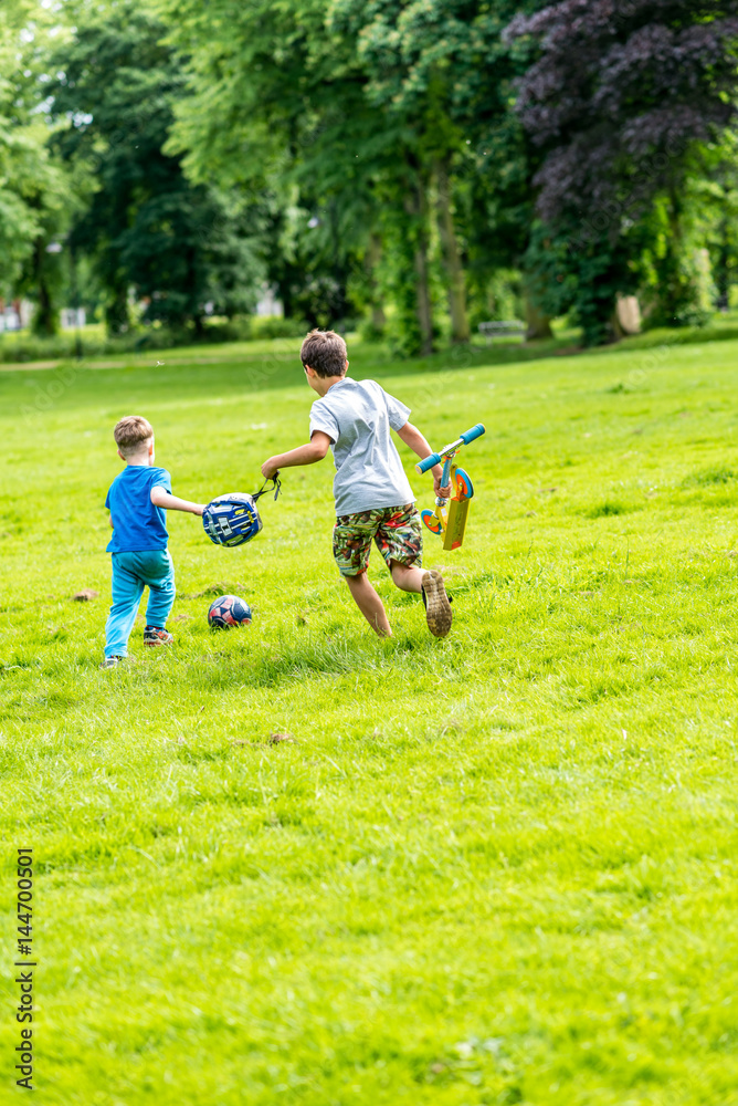 Day view of two boys playing football summer park Day view of two boys playing football summer park