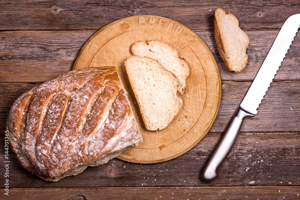 Crusty bread being cut on wooden chopping board Crusty bread being cut on wooden chopping board