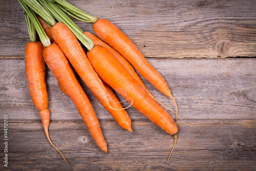 Bunch of fresh carrots over vintage wood background.