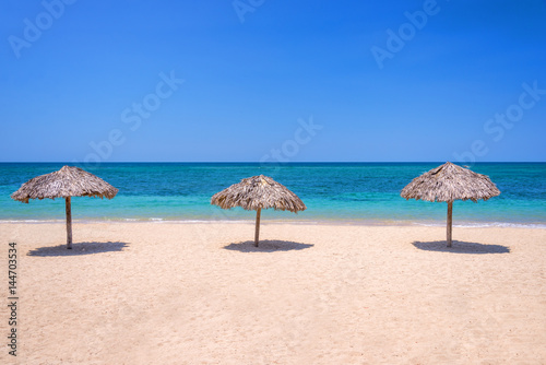 Straw umbrellas on a beautiful tropical beach © Delphotostock
