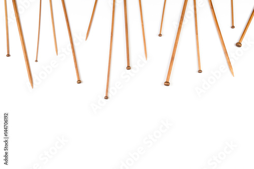 Wooden bamboo knitting needles arranged as frame border on white background