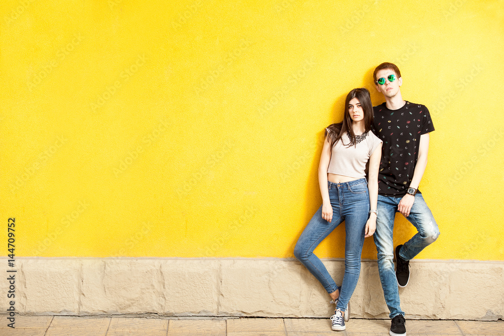 Couple posing in fashion style on yellow wall. Lifestyle and relationship