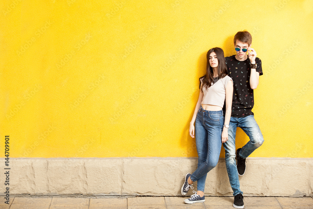 Young couple posing in fashion style on yellow wall. Lifestyle and relationship