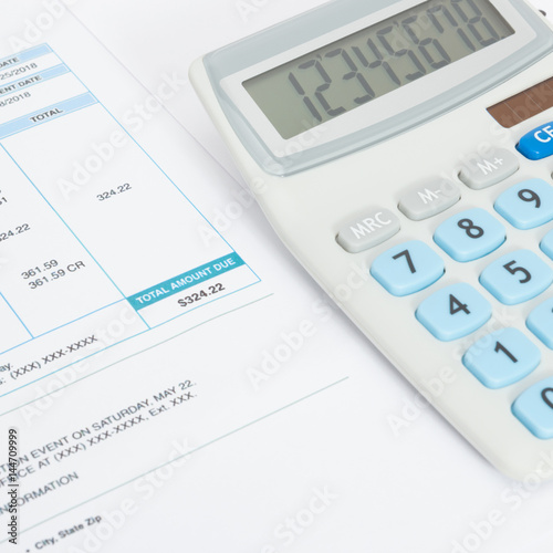 Close up studio shot of unpaid utility bill and calculator over it