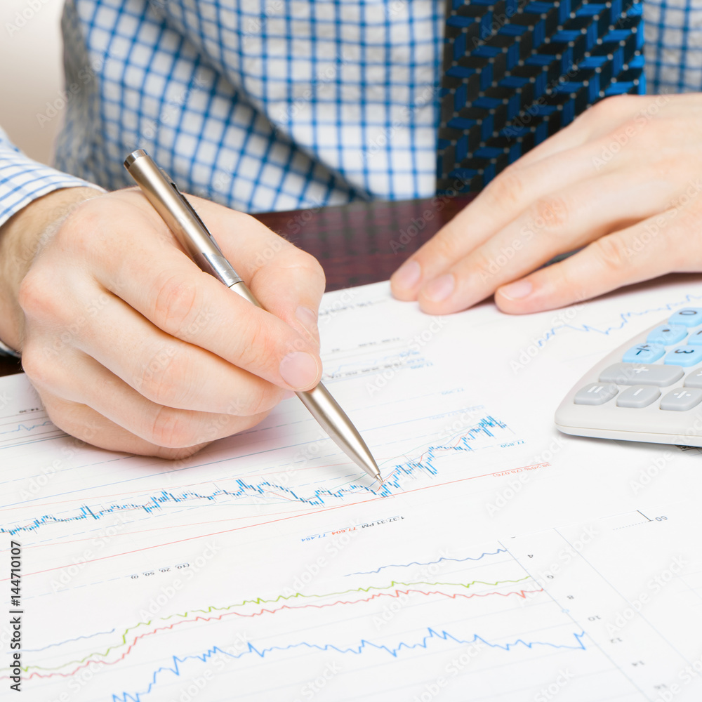 Banking, taxing and all things related with world of finance - close up studio shot of a man working with some financial data Banking, taxing and all things related with world of finance - close up studio shot of a man working with some financial data