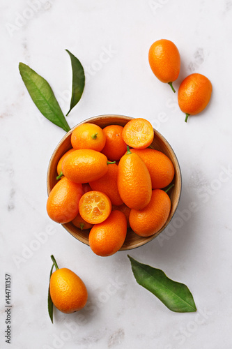 Flat lay of kumquats in a bowl on a marble background. Top view © virtustudio