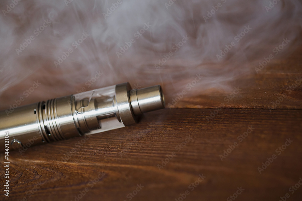 Electronic cigarette on a wooden table. Smoke.