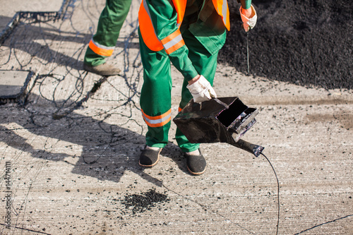 The man working asphalt pouring tar for road repair