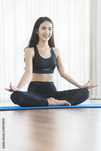 Young Asian woman practicing yoga. Girl is meditating. Copy space. Happiness, smiling.