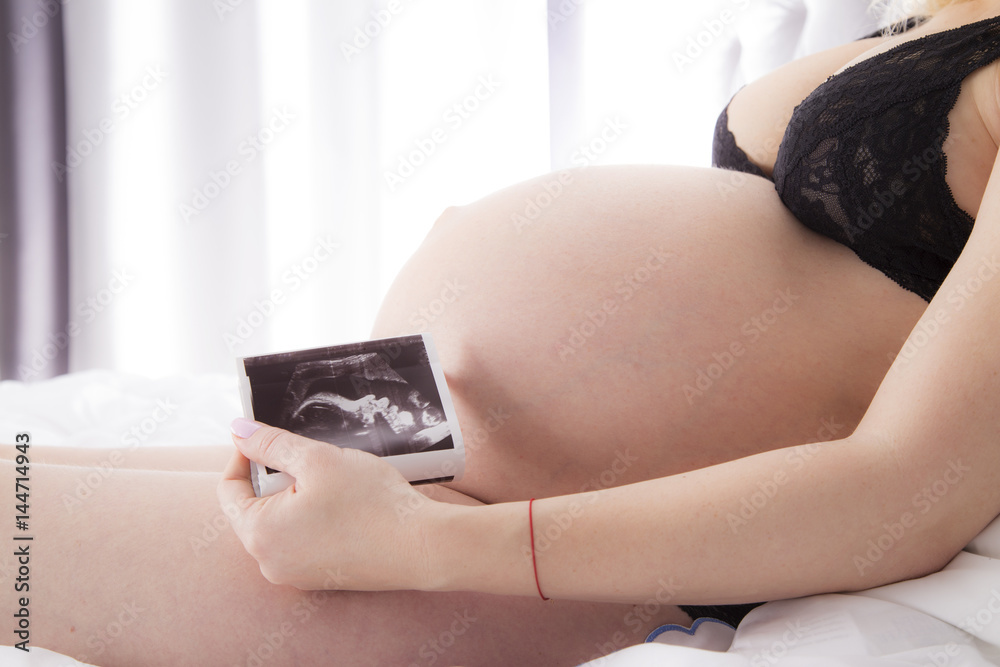 Kobieta w ciąży trzyma zdjęcie usg  - obrazy, fototapety, plakaty 