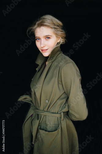 Portrait of lonely beautiful, cute, attractive, young, model blonde fashion student girl in green coat and curly hair posing at camera. Isolated on black. Tenderness and femininity. Pure beuaty. Angel