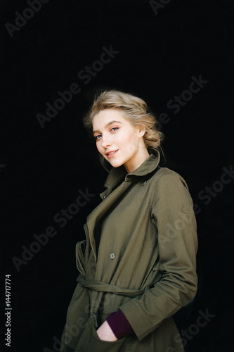 Portrait of lonely beautiful, cute, attractive, young, model blonde fashion student girl in green coat and curly hair posing at camera. Isolated on black. Tenderness and femininity. Pure beuaty. Angel