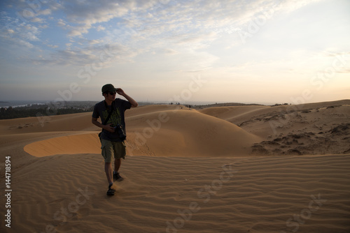 A man walking on sand dune and sunset time.