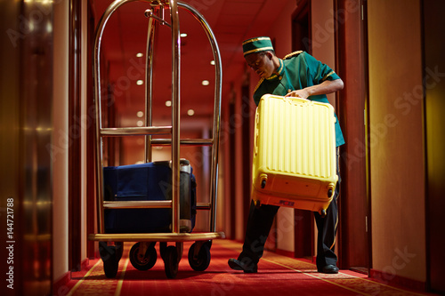 Fototapet Hotel servant taking out suitcase with baggage from hotel room