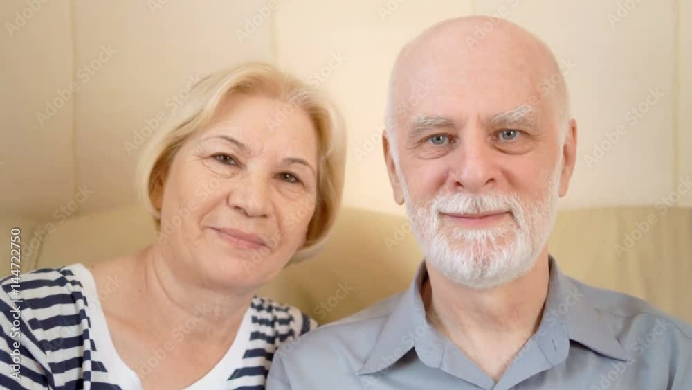 Portrait of cheerful good-looking senior couple sitting on sofa at home. Having good time relaxing. Portrait of cheerful good-looking senior couple sitting on sofa at home. Having good time relaxing.