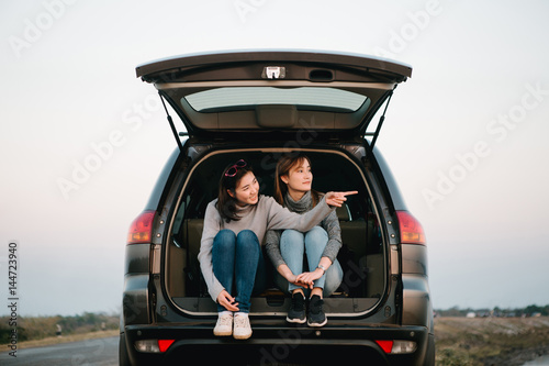 Two happy Asia woman friends enjoying road trip in hatchback car,flare light     © uinmine