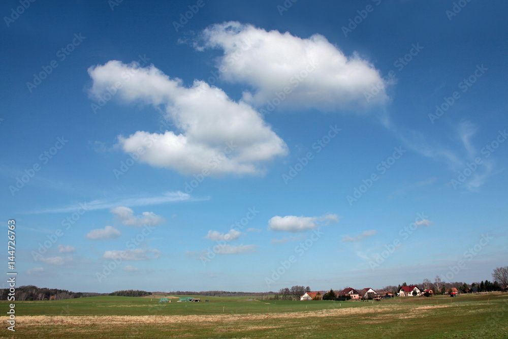 Naklejka premium Dorflandschaft mit weißen Wolken 