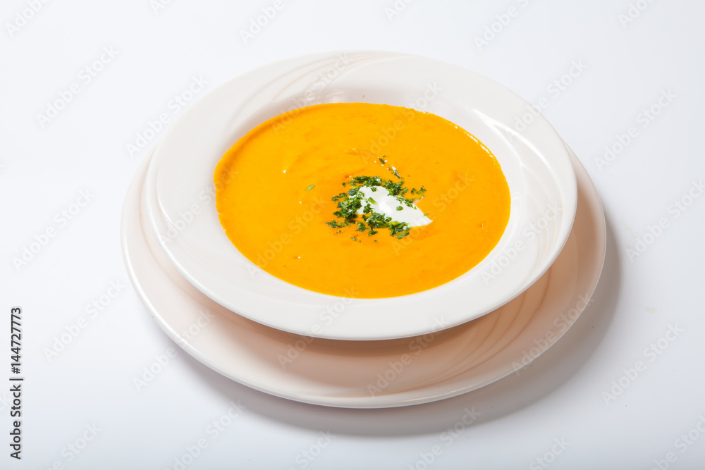 Homemade pumpkin soup with cream with spices on white plate Homemade pumpkin soup with cream with spices on white plate