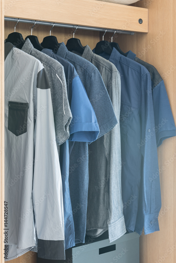 Obraz premium clothes hanging on rail in wooden wardrobe