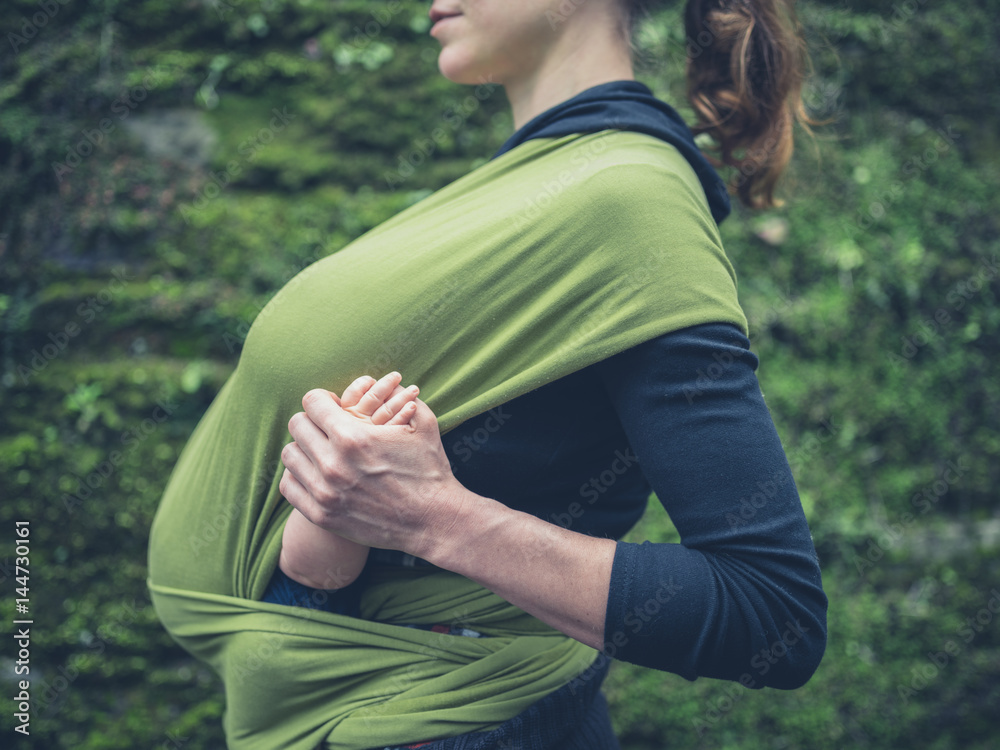 Young mother with baby in sling outside Young mother with baby in sling outside
