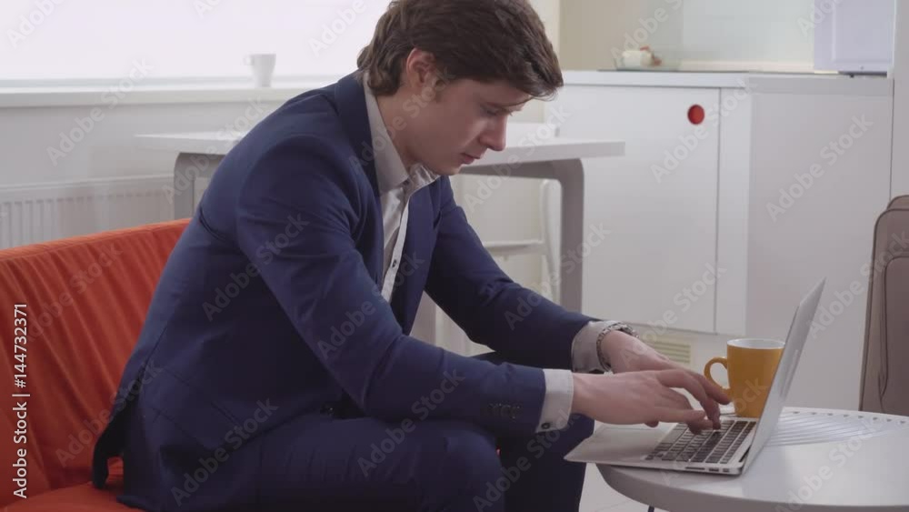 Portrait caucasian man working at home. Handsome businessman chatting online using computer sitting on sofa in apartment. Portrait caucasian man working at home. Handsome businessman chatting online using computer sitting on sofa in apartment.